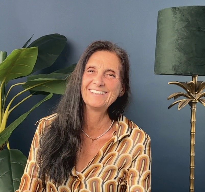 Roswitha Sion, Speakerin und BMS Coach, lächelnd vor Palmenlampe und Pflanzen