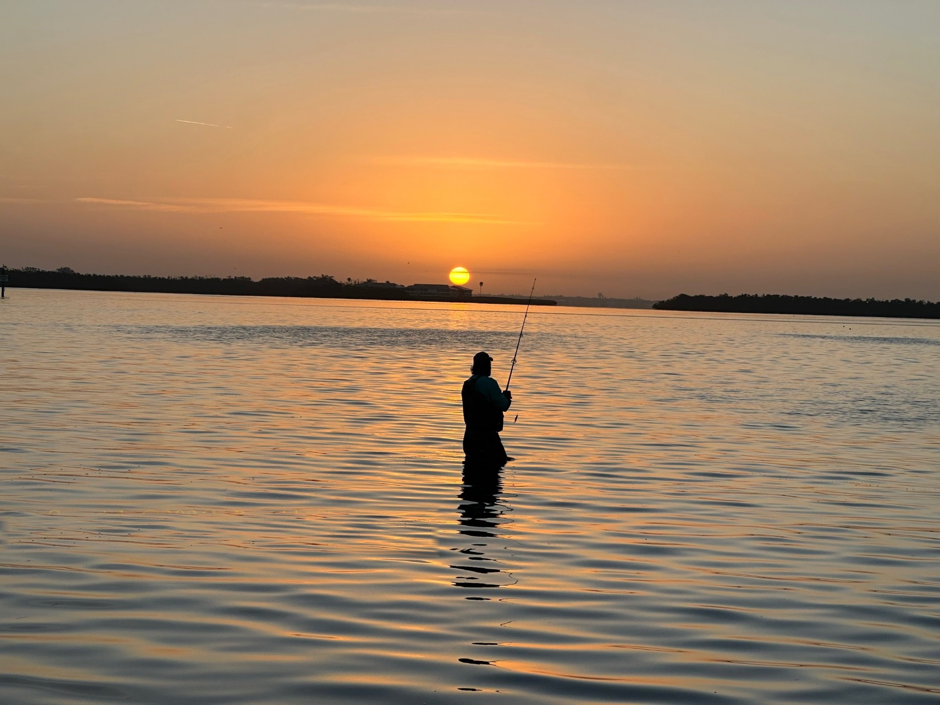 Angler bei goldenem Sonnenaufgang im ruhigen Wasser, Florida